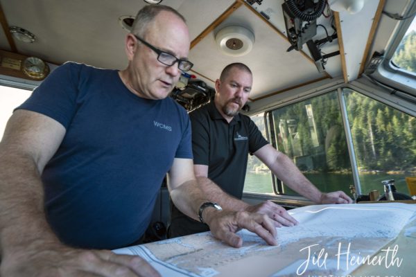 Corporal John Stringer and Constable Dale Judd use charts to plot a path through shallow water after the navigation power supply fails on the boat.